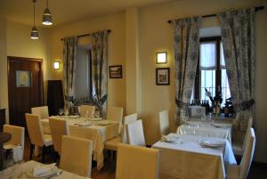 a restaurant with white tables and chairs and windows at Hotel Oberje Dla Viere Oulx - Check-in Automatico 24h in Oulx