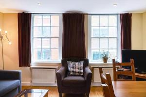 a living room with a chair and two windows at Lovely 2 - bedroom London Bridge apartment in London