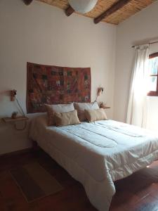 1 dormitorio con 1 cama blanca grande y ventana en Casona Inkill Huasi II en Tilcara