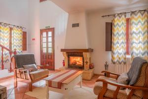 a living room with a fireplace and chairs at Cantinho Rural in Camacha