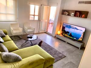 sala de estar con sofá amarillo y TV en Precioso Ático con las mayores vistas de Sevilla, en Tomares