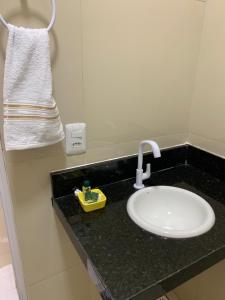 a white sink in a bathroom with a towel at Floripa Flat in Areia Branca