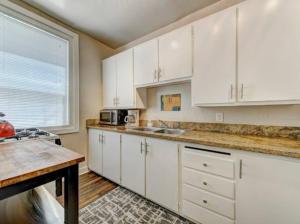 een keuken met witte kasten, een wastafel en een raam bij Perfect Location Walking Distance to Everything in Sacramento