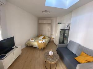 una pequeña sala de estar con sofá y cama en Bonito Estudio con terraza en Madrid