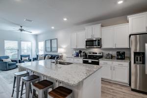 a kitchen with white cabinets and a kitchen island with bar stools at Serenity Island Treasure At 7868 Evening Glow Drive in Pensacola