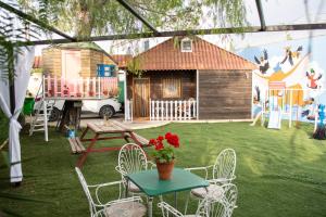 un patio con una mesa y sillas y una casa en Bungalow Perotonar Ideal Para Familia Con Niños, en La Puebla de Cazalla