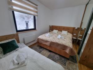 two beds in a small room with a window at Cozy Ski Apartment Jahorina in Jahorina