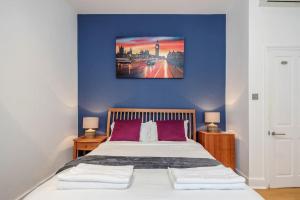 een slaapkamer met een blauwe muur en een bed met paarse kussens bij Luxurious Mews House in Londen