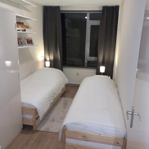 two beds in a small room with a window at KeyCity Apt Near Amsterdam & The Hague in Leiden