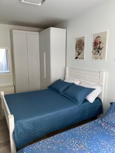 - une chambre avec un lit bleu et une armoire blanche dans l'établissement NOVO Mar Doce Lar Pé na Areia, à Balneário Camboriú