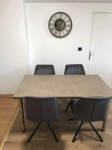 a table with two chairs and a clock on a wall at Le p’tit Bragard in Saint-Dizier