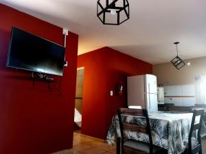 um quarto com uma parede vermelha com uma televisão e uma mesa em Jazmin del Cielo em Capilla del Monte