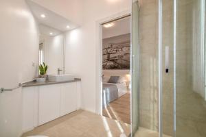 bagno con doccia in vetro e lavandino di RelaisApartments MERCEDE - Extraordinary Hospitality ad Alghero
