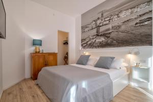 una camera con un letto bianco e un dipinto sul muro di RelaisApartments MERCEDE - Extraordinary Hospitality ad Alghero