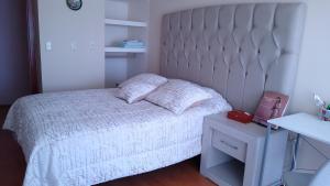 1 dormitorio con cama blanca y mesa blanca en Habitación matrimonial con cama y sofá para cuatro personas en Tlaxcalancingo