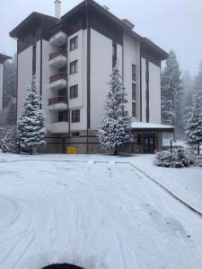 a building with snow on the ground in front of it at HQ Apartment Flora Violet in Borovets