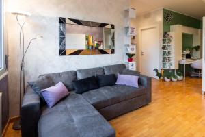 a living room with a gray couch with purple pillows at Appartamento a Modena, comodo a tutti i servizi in Modena