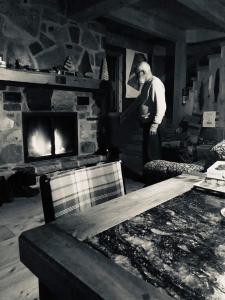 a man standing in a living room with a fireplace at Le Refuge de mon père in Sacré-Coeur-Saguenay