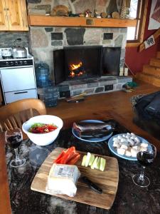 a kitchen with a table with food and a fireplace at Le Refuge de mon père in Sacré-Coeur-Saguenay