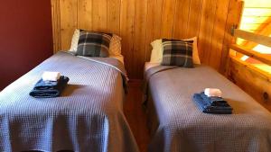 Habitación con 2 camas individuales y paredes de madera. en Le Refuge de mon père en Sacré-Coeur-Saguenay