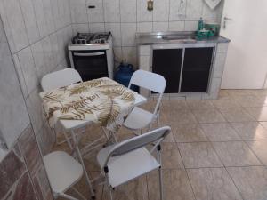 a kitchen with white chairs and a table and a stove at Meu Cantinho E in Guaratinguetá