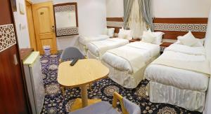 a hotel room with three beds and a table at راحة الوفود الفندقيه in Al Khansāk +17 photos