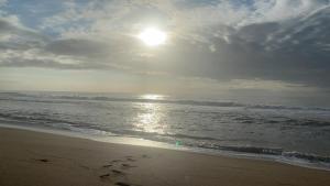 une plage avec des empreintes sur le sable et l'océan dans l'établissement 7th Heaven, à Tugela Mouth