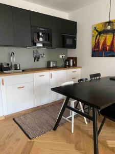 une cuisine avec des placards blancs et une table avec des chaises dans l'établissement BOTKa apartmán, à Tatranska Strba