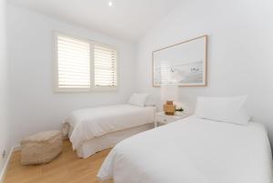 - une chambre blanche avec 2 lits et une fenêtre dans l'établissement Surf Beach House, à Shellharbour