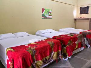 two beds in a room with red blankets on them at Hotel Casa Vieja in La Ceiba