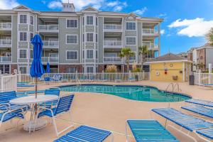 a pool with chairs and a table and a building at Ground Floor 3 Bedroom Condo! Magnolia Pointe 105! Sleeps 6 guests in Myrtle Beach