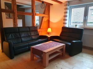 Sala de estar con 2 sofás de cuero y mesa de centro en TAN - Ferienhaus Kleine Bergstraße 2 - Fam Rüdiger, en Tanne