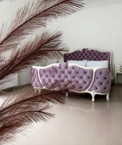 a purple couch in a room next to a palm tree at Krioklio Namelis Verkiuose in Vilnius