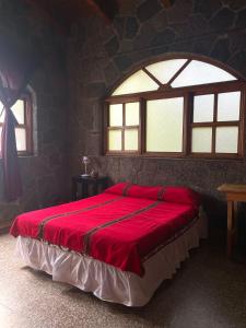 1 dormitorio con 1 cama grande de color rojo y ventana en Casa Qatzij - Guest House, Lake Atitlan, en San Lucas Tolimán