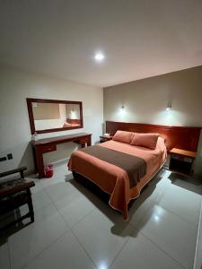 een slaapkamer met een bed, een spiegel en een bureau bij Hotel Latino in Sahuayo de José María Morelos