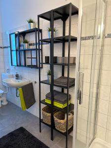 a bathroom with a black shelf with towels and a sink at bee Design Apartment + Zentral + Küche + Parken in Wetzlar