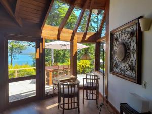 ein Esszimmer mit Tisch und Stühlen und Fenstern in der Unterkunft Casa del Sur Villa La Angostura in Villa La Angostura