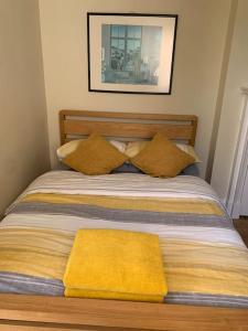 a bed with two pillows and a yellow blanket on it at Walkers Rest! in Alfriston