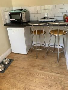 a kitchen with two bar stools and a microwave at Walkers Rest! in Alfriston