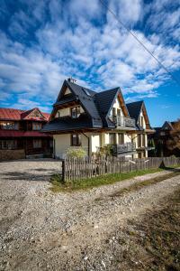 a house with a black roof and a fence at Domki Bukowianka in Murzasichle