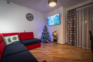 a christmas tree in a living room with a red couch at Domki Bukowianka in Murzasichle