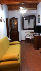 a living room with a yellow couch and a tv at La Casa dei Nonni in Castagneto Carducci