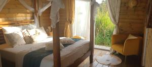 a bedroom with a bed and a chair and a window at L'écrin Vert in Sainte-Anne