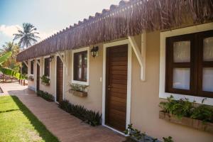 a house with a wooden door and a yard at Pousada Reserva Tatuamunha in Pôrto de Pedras