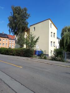 an empty street with a white building and trees at Urlaub nicht nur für Monteure "K3" in Gera