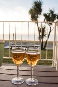 two glasses of wine sitting on a table with the beach at Inn of the Four Winds Seaside Oceanfront in Seaside
