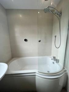 a white bathroom with a tub and a sink at The Cottage, a perfect getaway! in Southport