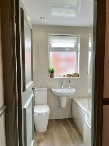 baño con aseo y lavabo y ventana en The Cottage, a perfect getaway! en Southport