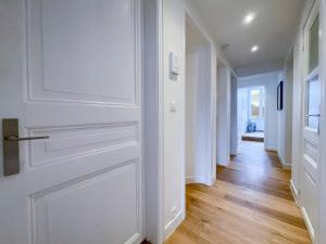 a hallway with a white door and wooden floors at Appartement spacieux & calme avec vue sur l'Escaut in Tournai