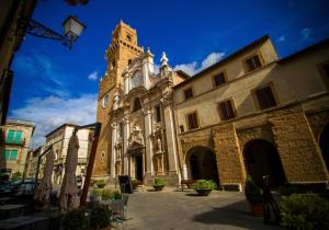 a large building with a clock tower on top at La Casa Degli Archi in Pitigliano